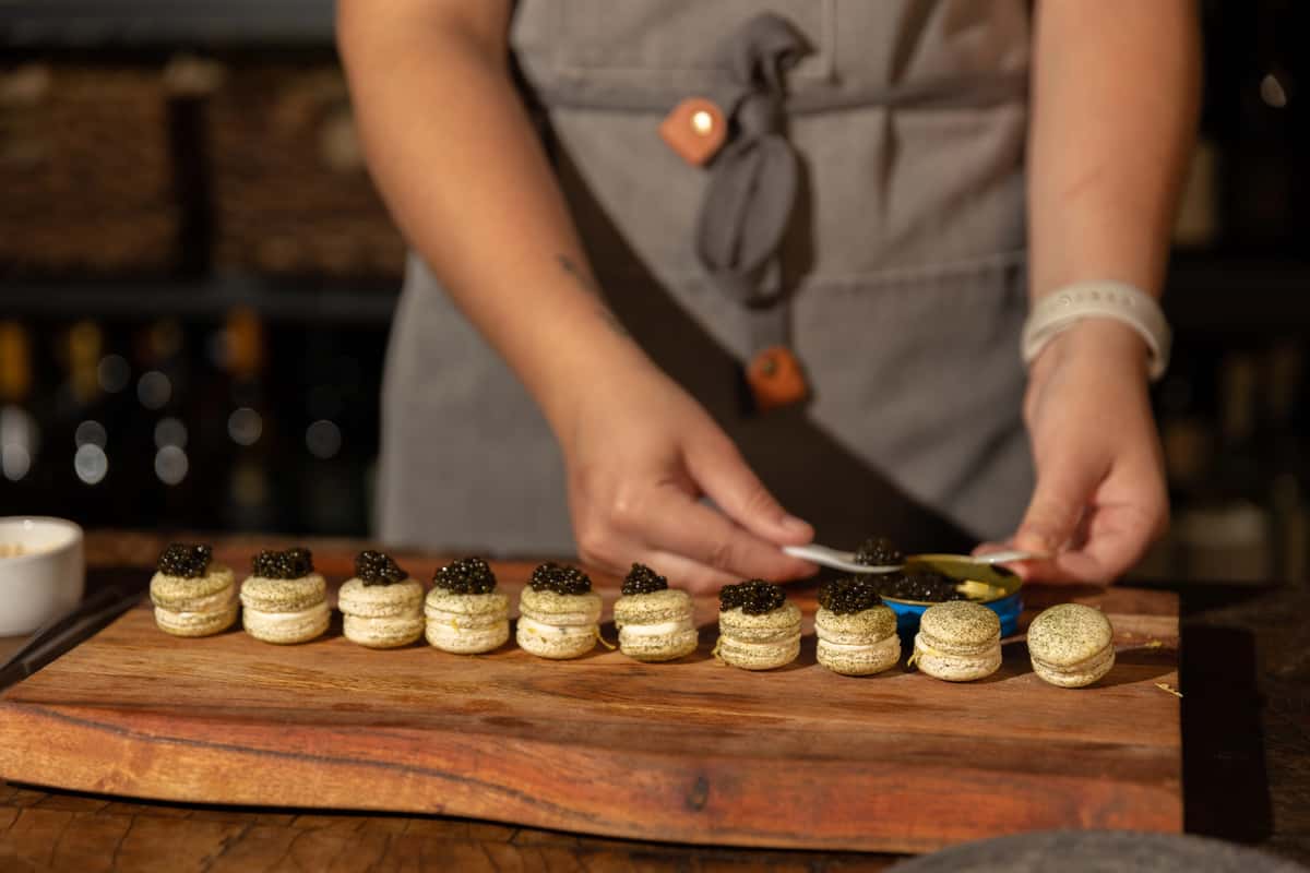 Chef carefully plating gourmet macarons topped with caviar for a luxury dining experience