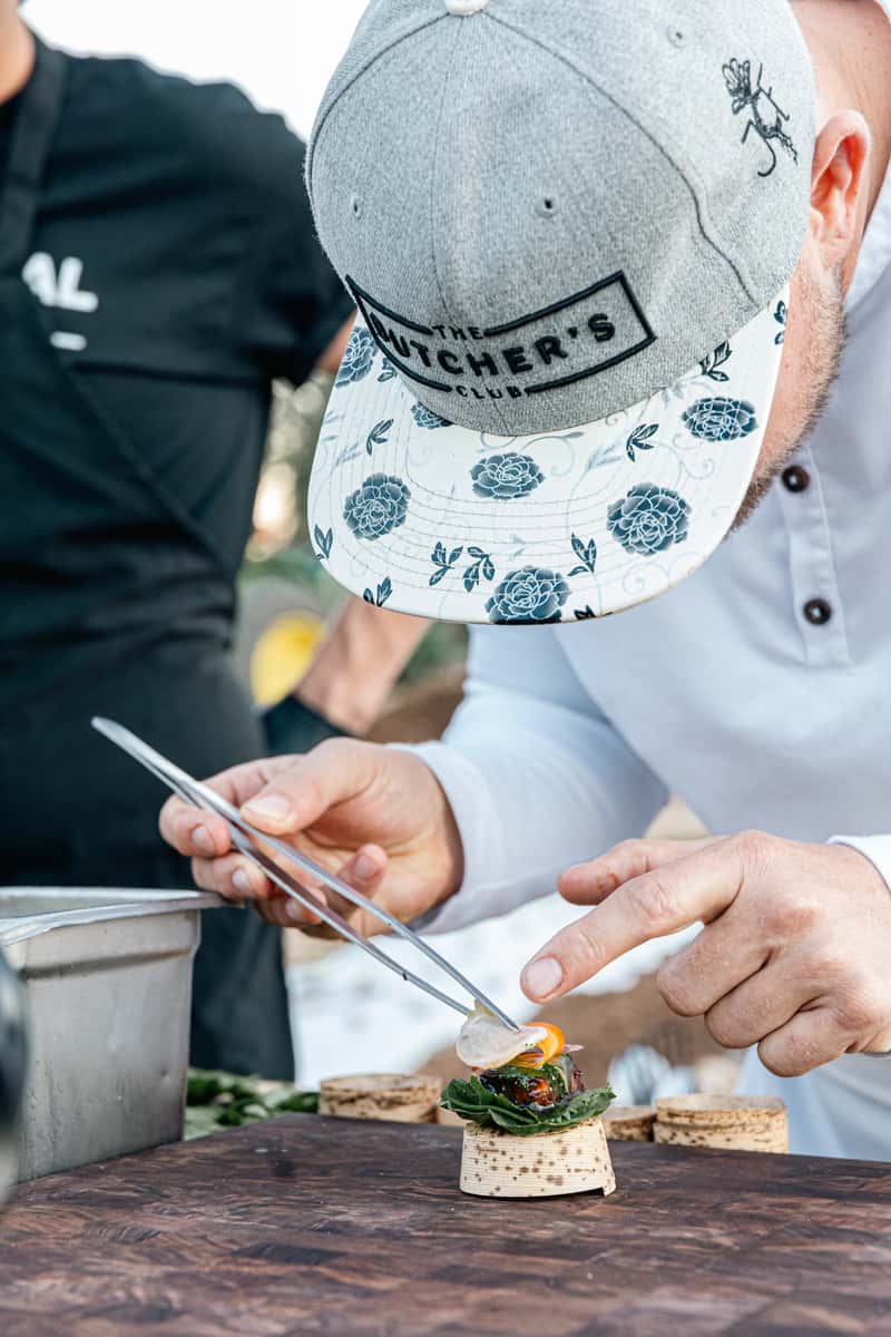 Chef using tweezers to carefully plate a small gourmet appetizer