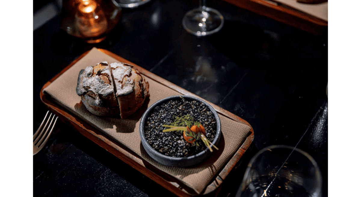 Artisan bread course served with gourmet accompaniments in an elegant fine dining restaurant with candlelit ambiance.