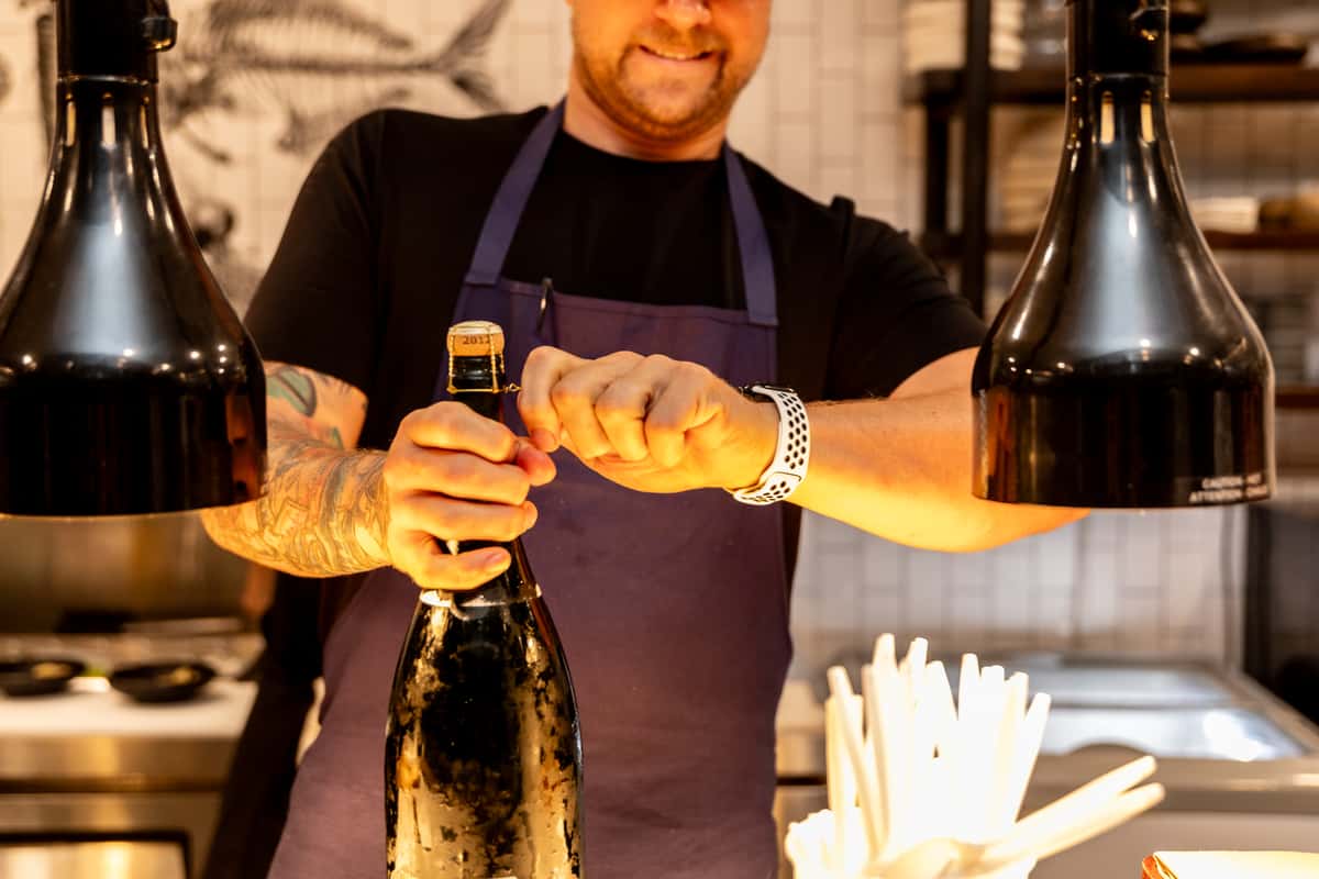 Chef opening a wine bottle during professional fine dining wine service