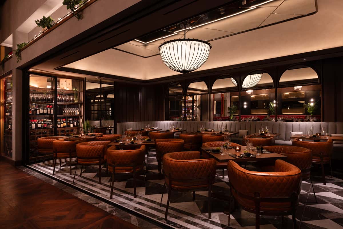 Elegant restaurant dining room with leather chairs, wine cellar, and warm ambient lighting
