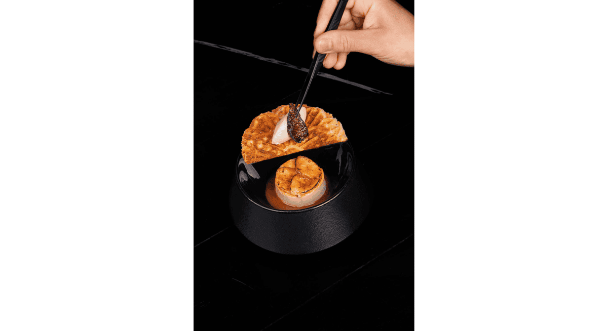 Elegant gourmet dessert with caramelized fruit and waffle garnish being finished with a spoon in a fine dining presentation.