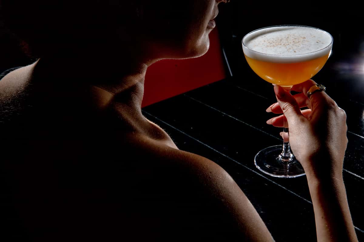 Guest holding a craft cocktail in a dimly lit upscale bar setting