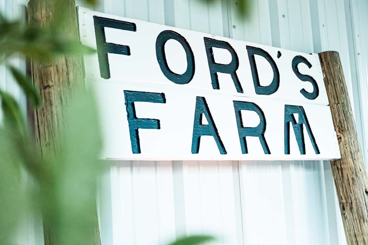 Ford's Farm sign mounted on wooden posts against a white corrugated wall