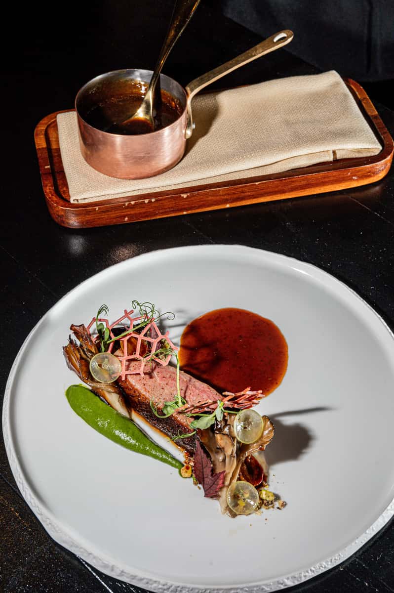 Gourmet seared meat dish with colorful vegetables and sauce served on a fine dining plate
