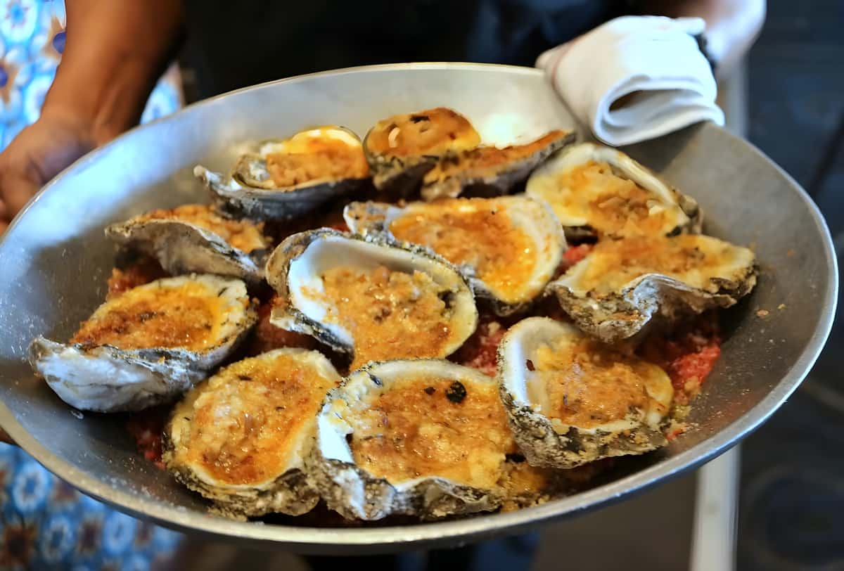 Baked oysters topped with seasoned cheese and herbs, served fresh from the kitchen.