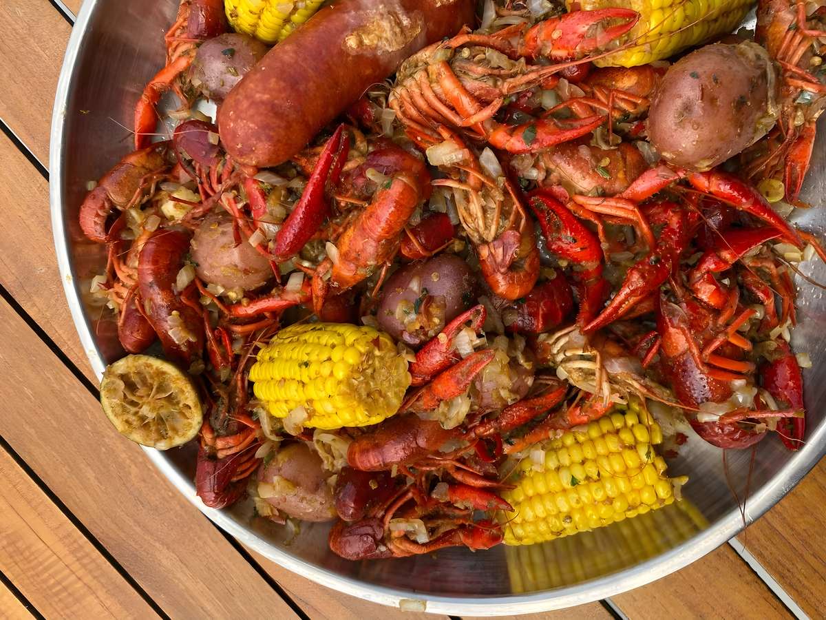 Traditional seafood boil with crawfish, sausage, corn, and potatoes seasoned with bold flavors.