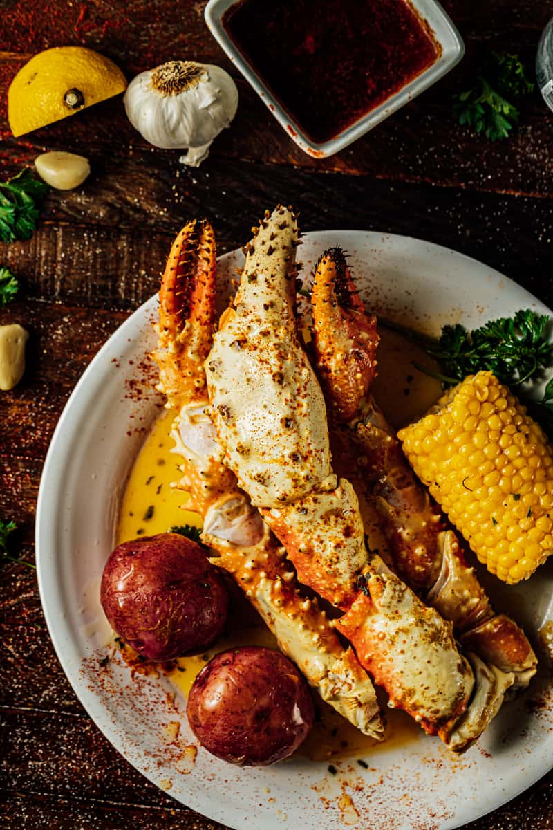 Indulgent crab leg seafood boil paired with red potatoes, corn on the cob, and greens in a lemon butter sauce.