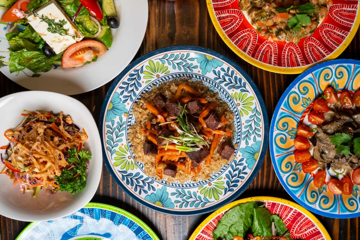A vibrant spread of halal dishes, featuring flavorful rice topped with tender beef and carrots, fresh salad, colorful appetizers, and garnished plates, showcasing multi-cultural cuisine.