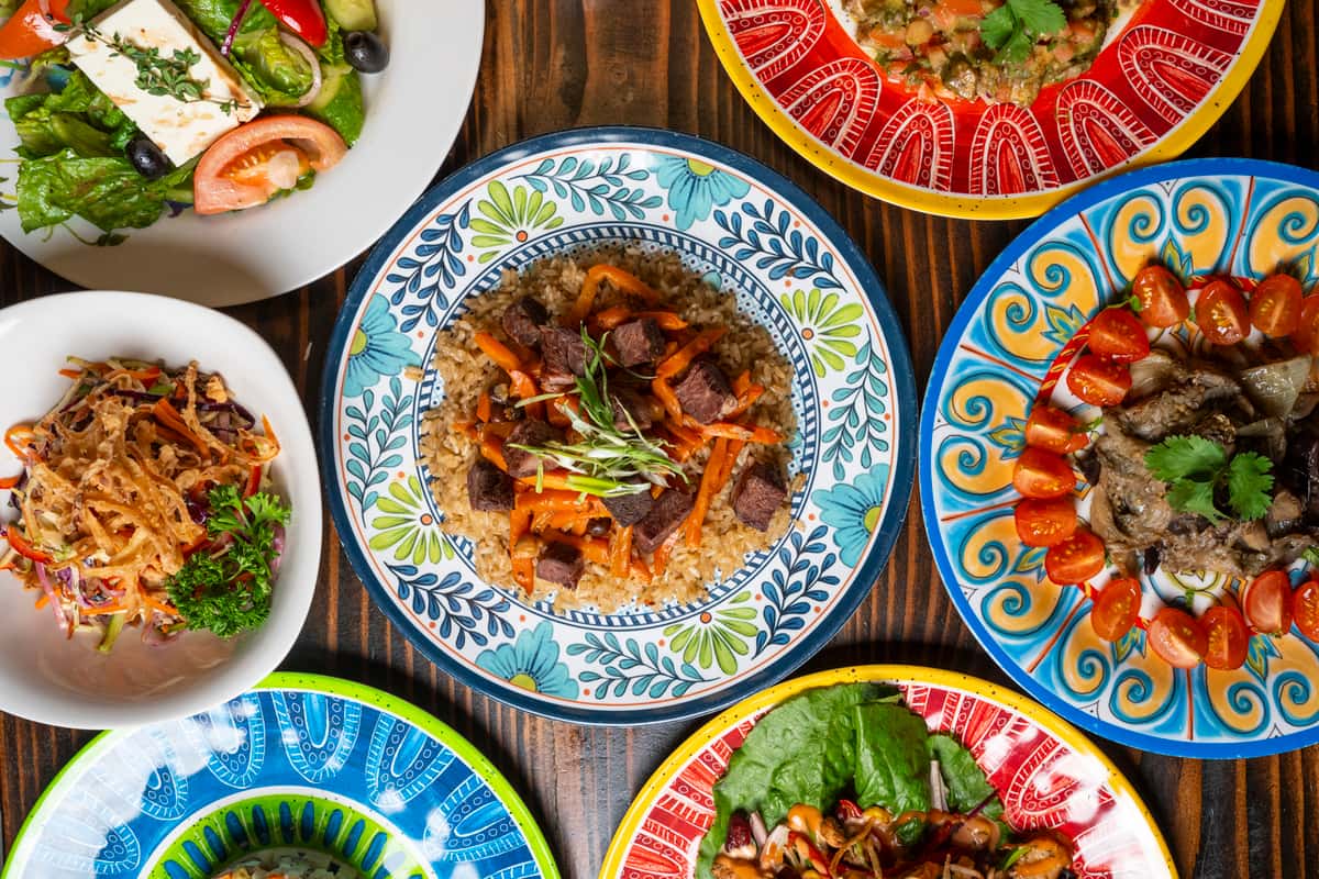 A vibrant spread of halal dishes, featuring flavorful rice topped with tender beef and carrots, fresh salad, colorful appetizers, and garnished plates.