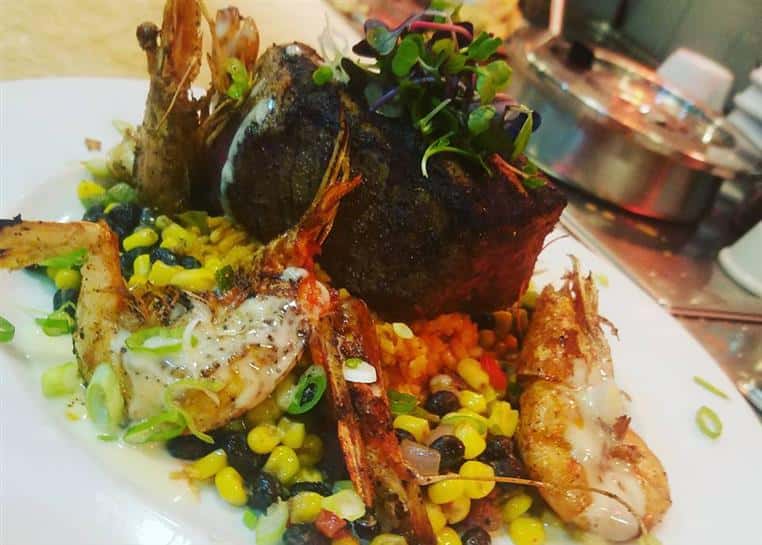 Steak and shrimp over corn, beans, tomatoes