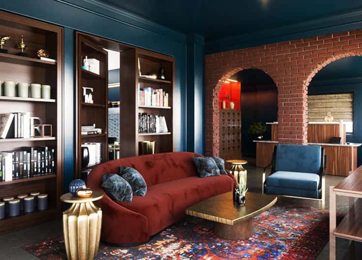 Elegant lounge with a red velvet sofa, blue armchair, gold side tables, brick archways, bookshelves, and a colorful patterned rug.Elegant lounge with a red velvet sofa, blue armchair, gold side tables, brick archways, bookshelves, and a colorful patterned rug.Elegant lounge with a red velvet sofa, blue armchair, gold side tables, brick archways, bookshelves, and a colorful patterned rug.