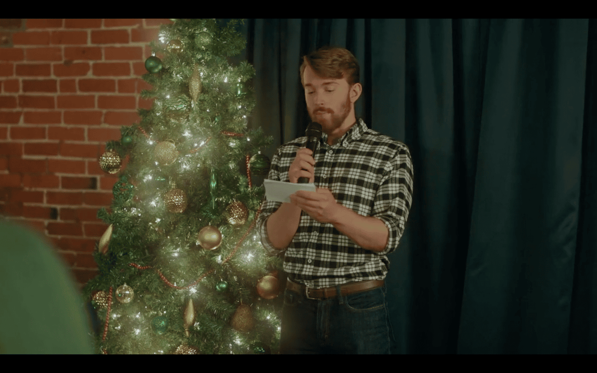 Man next to a Christmas tree reading trivia questions