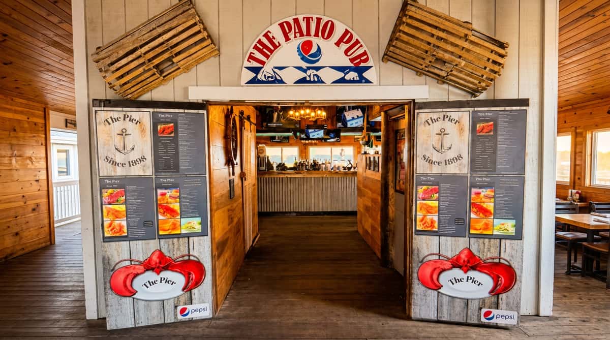 Exterior of "The Patio Pub" entrance with lobster traps, wooden doors displaying menus, and a view into the bar.