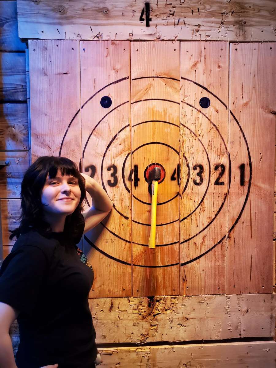 Person standing beside axe throwing board