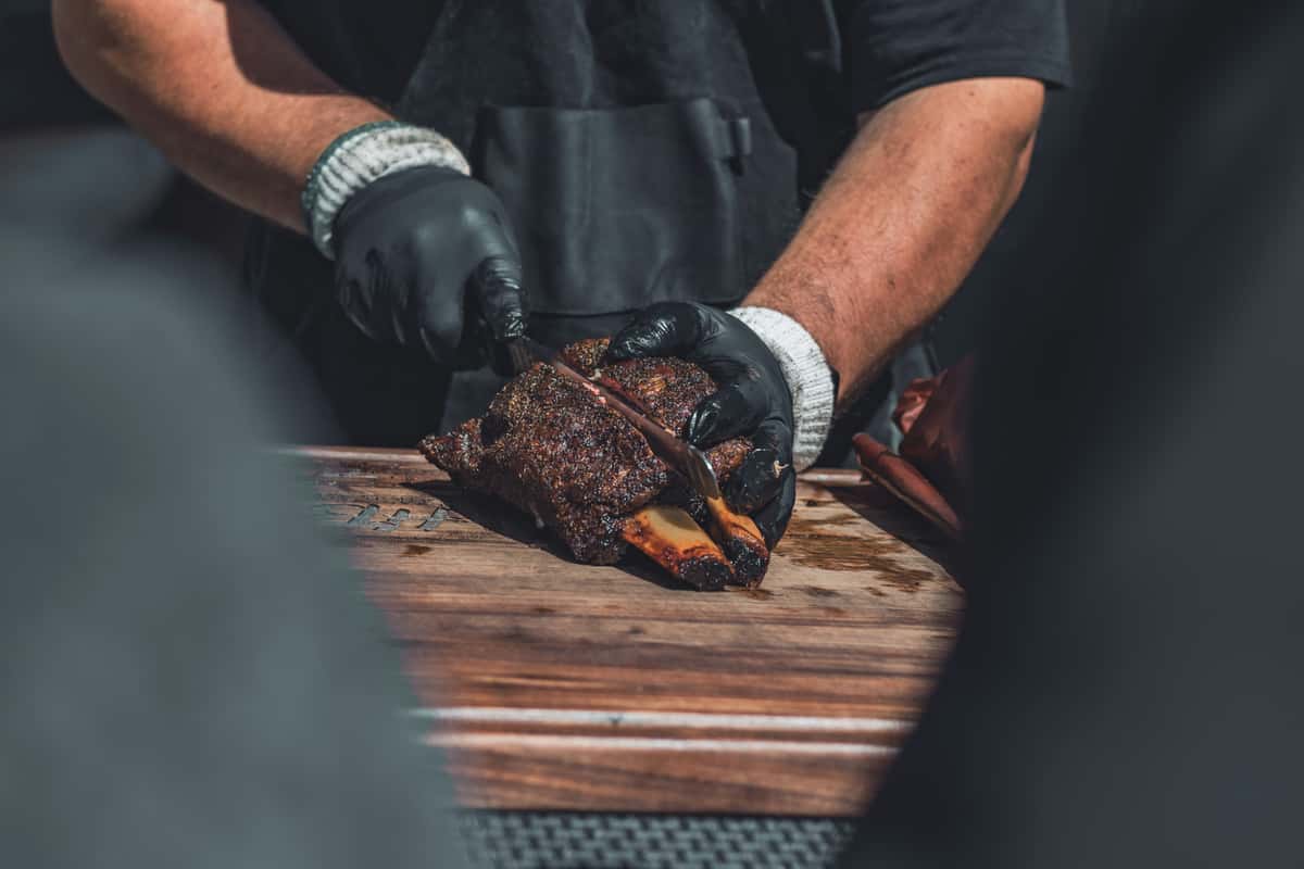 A person cutting into a rack of ribs
