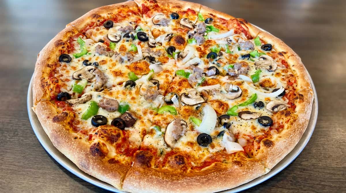 Pizza topped with melted cheese, sausage, mushrooms, black olives, green peppers, and onions.
