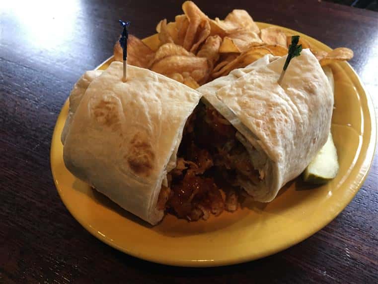 Wrap with side of potato chips and pickle on a dish.