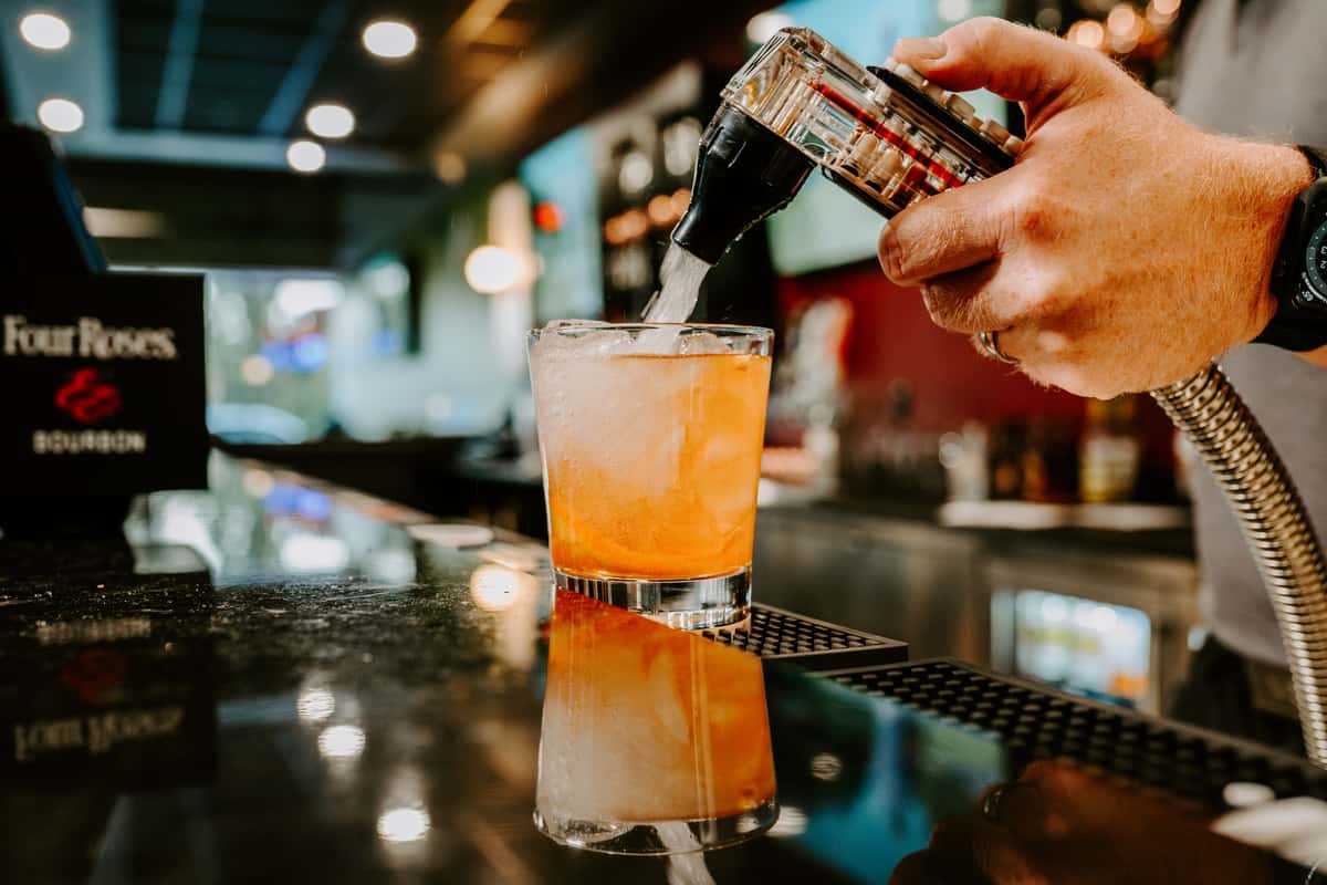 A bartender filling a glass with bourbon