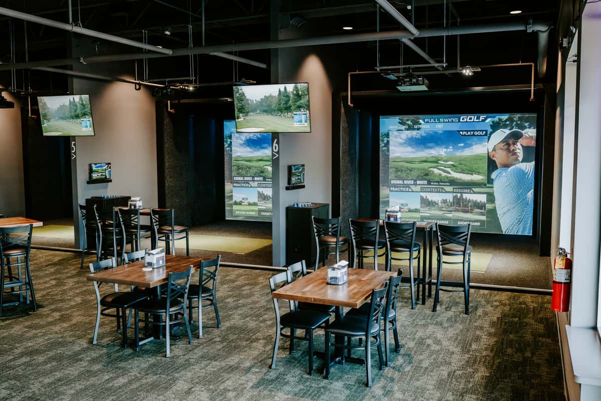 A larger space with lots of seating at the indoor golf restaurant