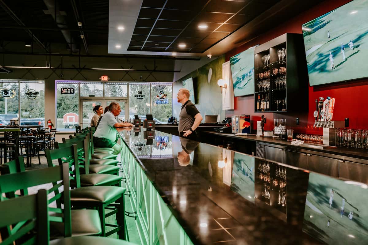 Bar section of Links and Drinks with a display of many available drinks and the bartender chatting to customers