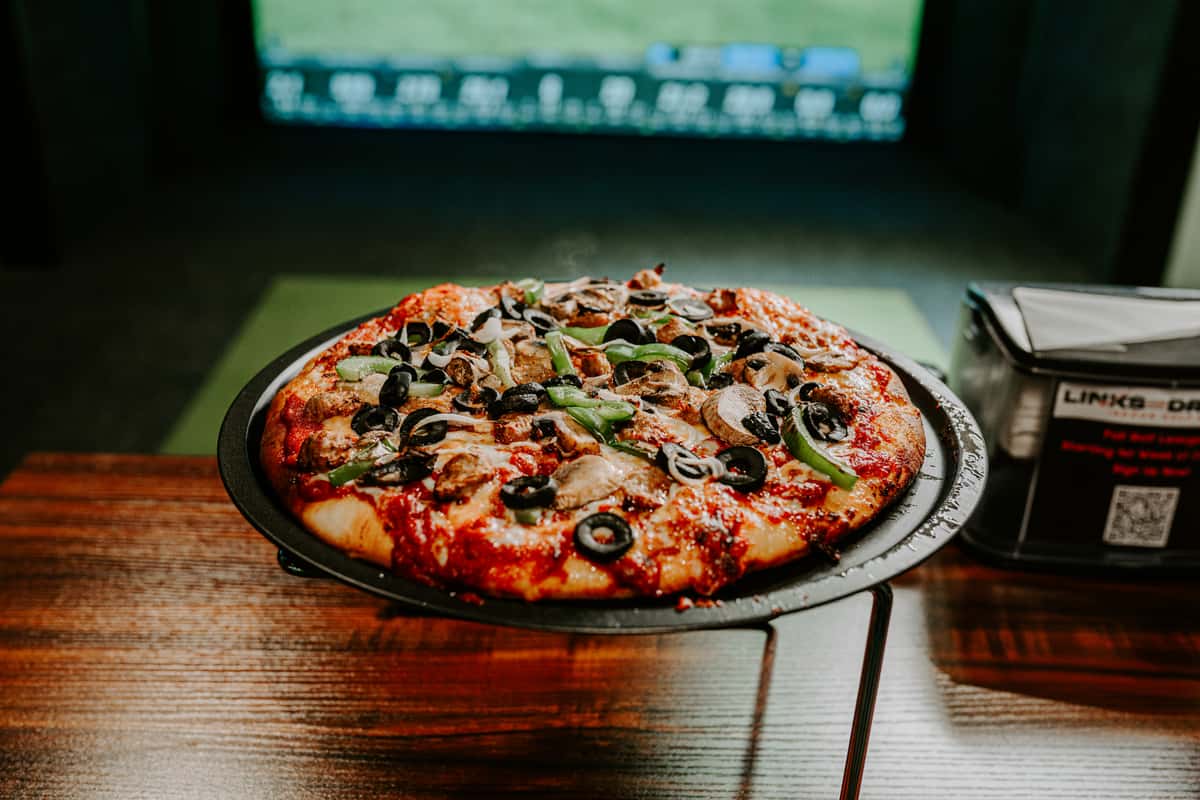 A large pizza on a stand with a variety of fresh toppings