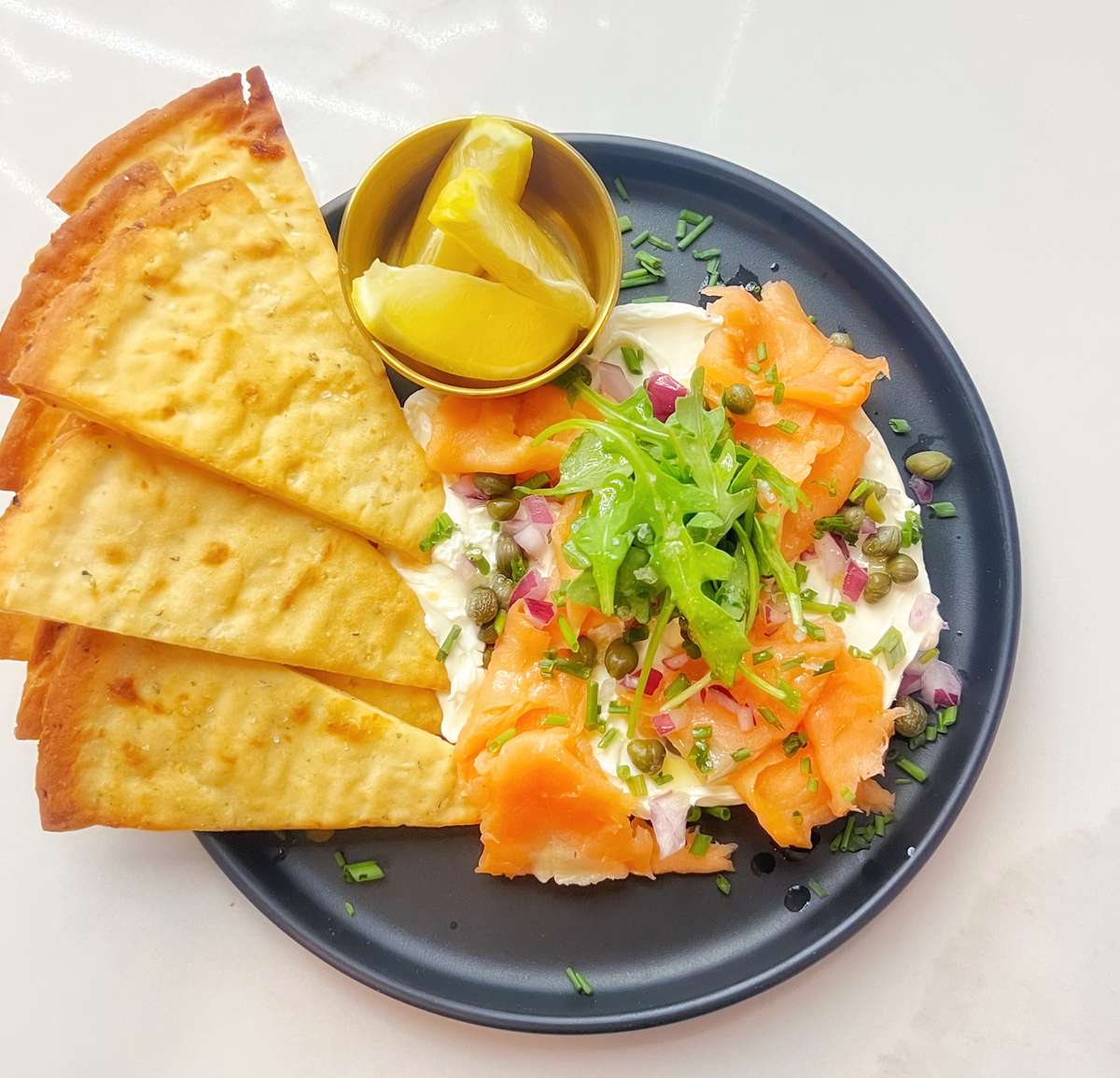 Smoked salmon, flaked, and perched on whipped organic cream cheese; dressed with diced red onion, capers, fresh chives, arugula, lemon oil and hand flaked sea salt
