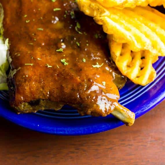 ribs on a plate with a side of waffle fries