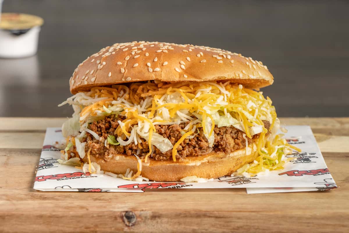 Texas Tom's taco burger loaded with seasoned beef, lettuce, and shredded cheese on a sesame seed bun