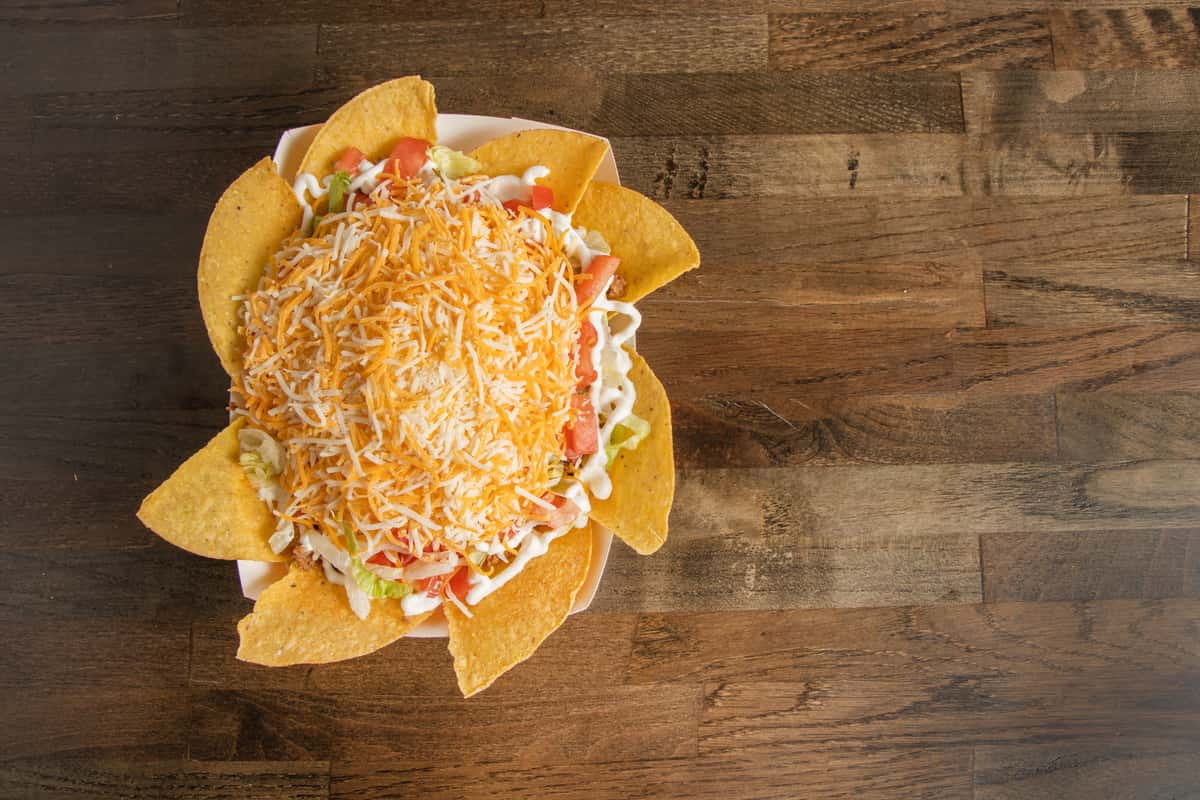Texas Tom's taco salad loaded with seasoned meat, lettuce, tomatoes, shredded cheese, and crispy tortilla chips