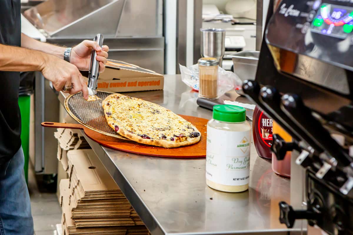 Fresh pizza being prepared in the kitchen at Jimmy's Burgers & Pizza in Hurst, TX