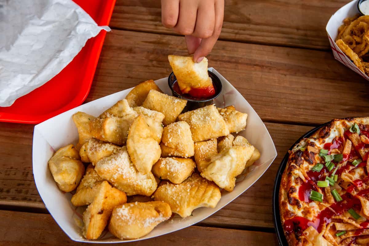 Parmesan puff bites being dipped in sauce at Jimmy's Burgers & Pizza in Hurst, TX