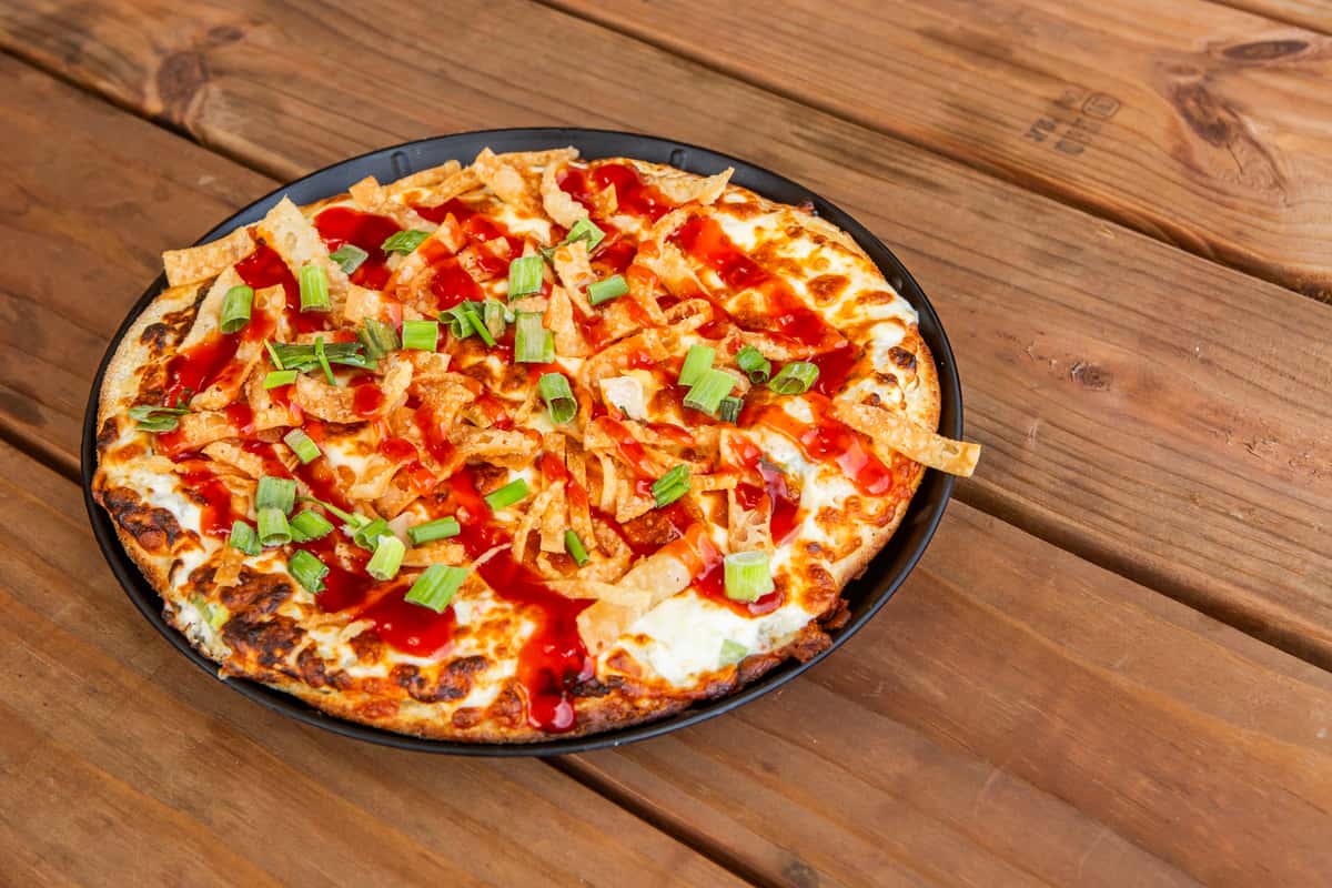 Crab Rangoon pizza topped with green onions and sweet chili sauce at Jimmy's Burgers & Pizza