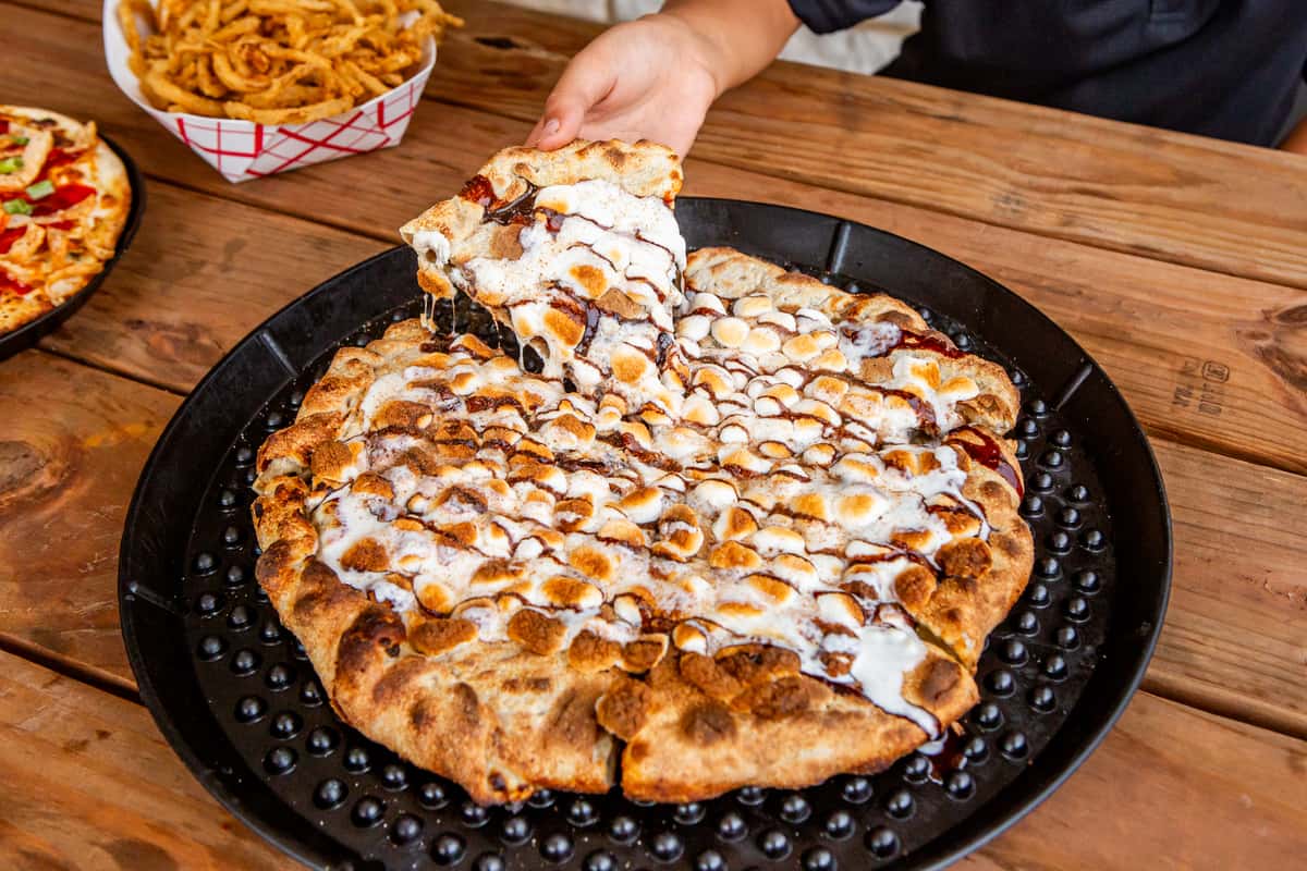 S'mores dessert pizza being finished with sweet drizzle at Jimmy's Burgers & Pizza
