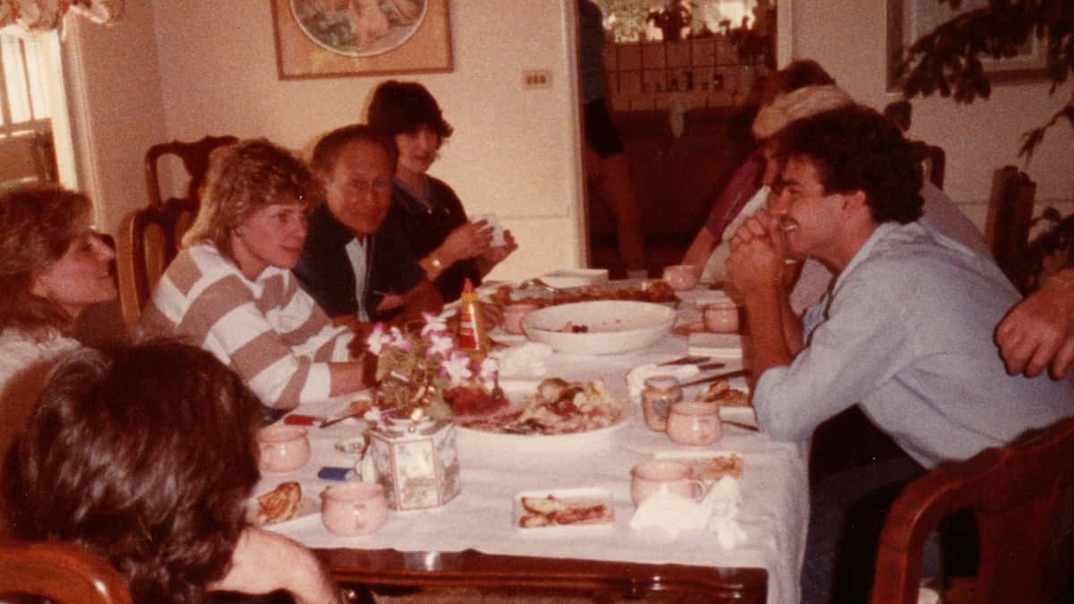 Old photo of Maddy and Family sitting around the dinner table enjoying a meal.