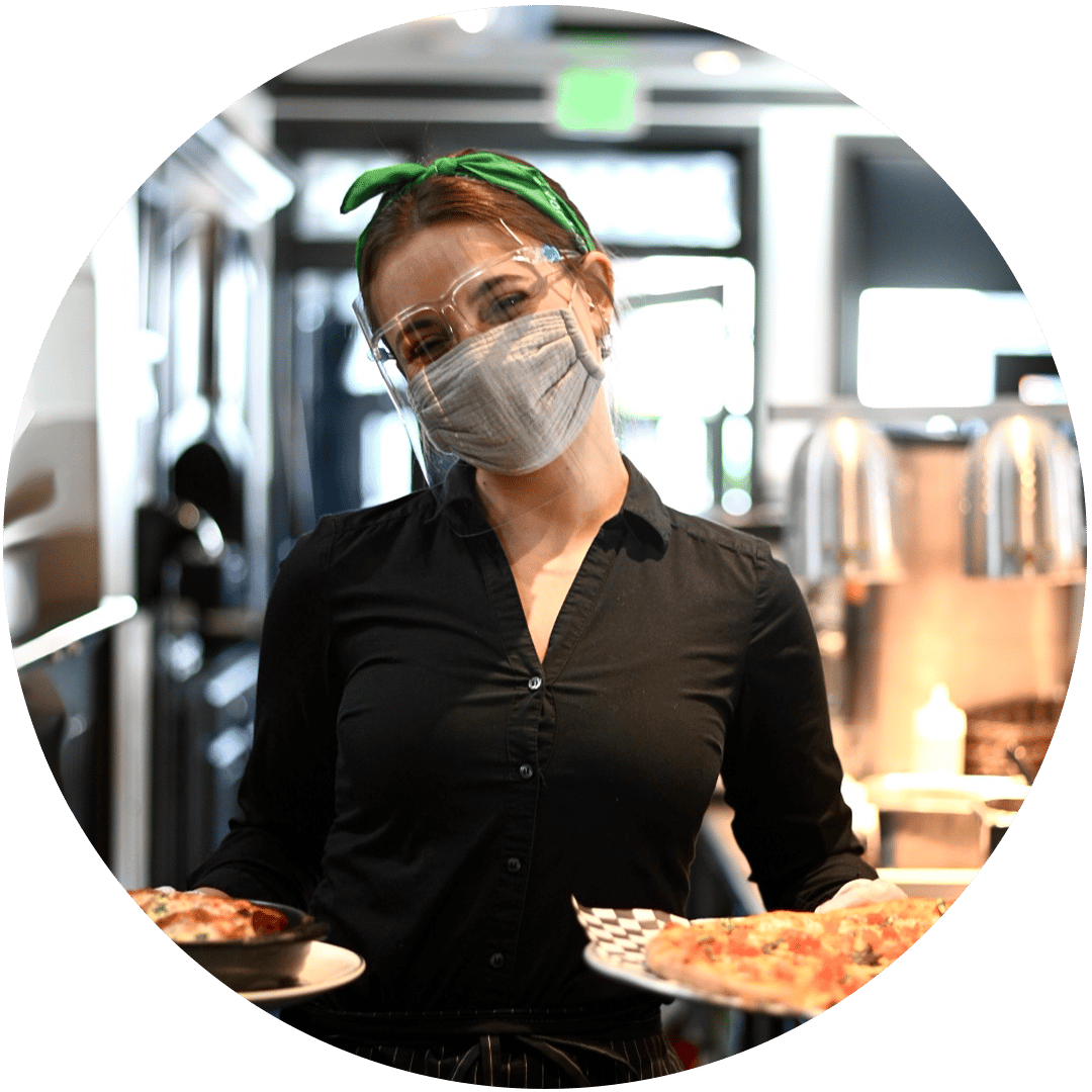 Picture of female maria's employee holding trays of food, smiling, wearing health safety mask