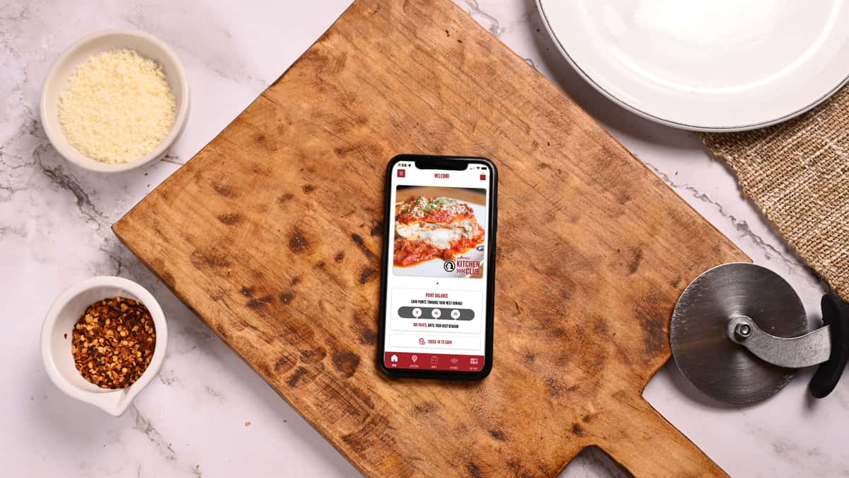 Cell phone on a wooden cutting board showing our App homescreen