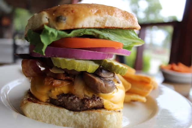MCC Stacked Hamburger loaded with toppings such as farm to table lettuce, tomatoes, onions, housemade pickles and more.