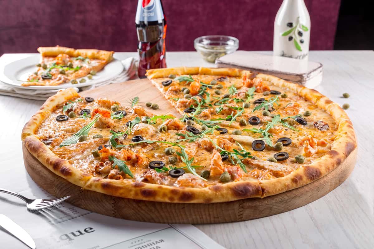 Pizza with toppings served alongside a bottle of soda