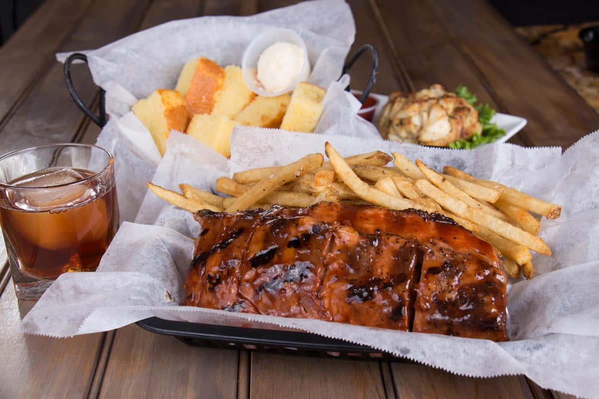 baby back ribs in a basket with fries, corn bread on the side and jumbo lump crab cake