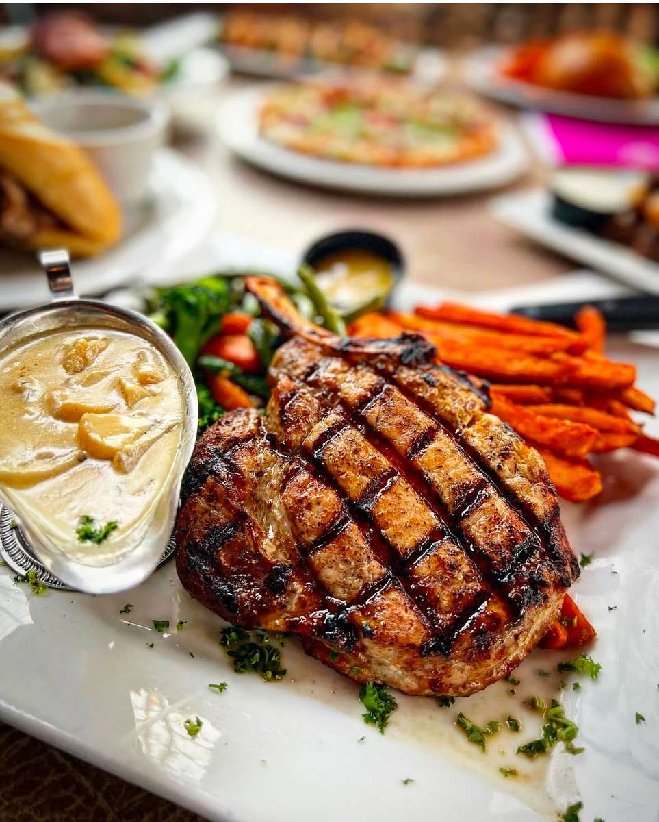 Steak with a side of fresh vegetables and a sauce