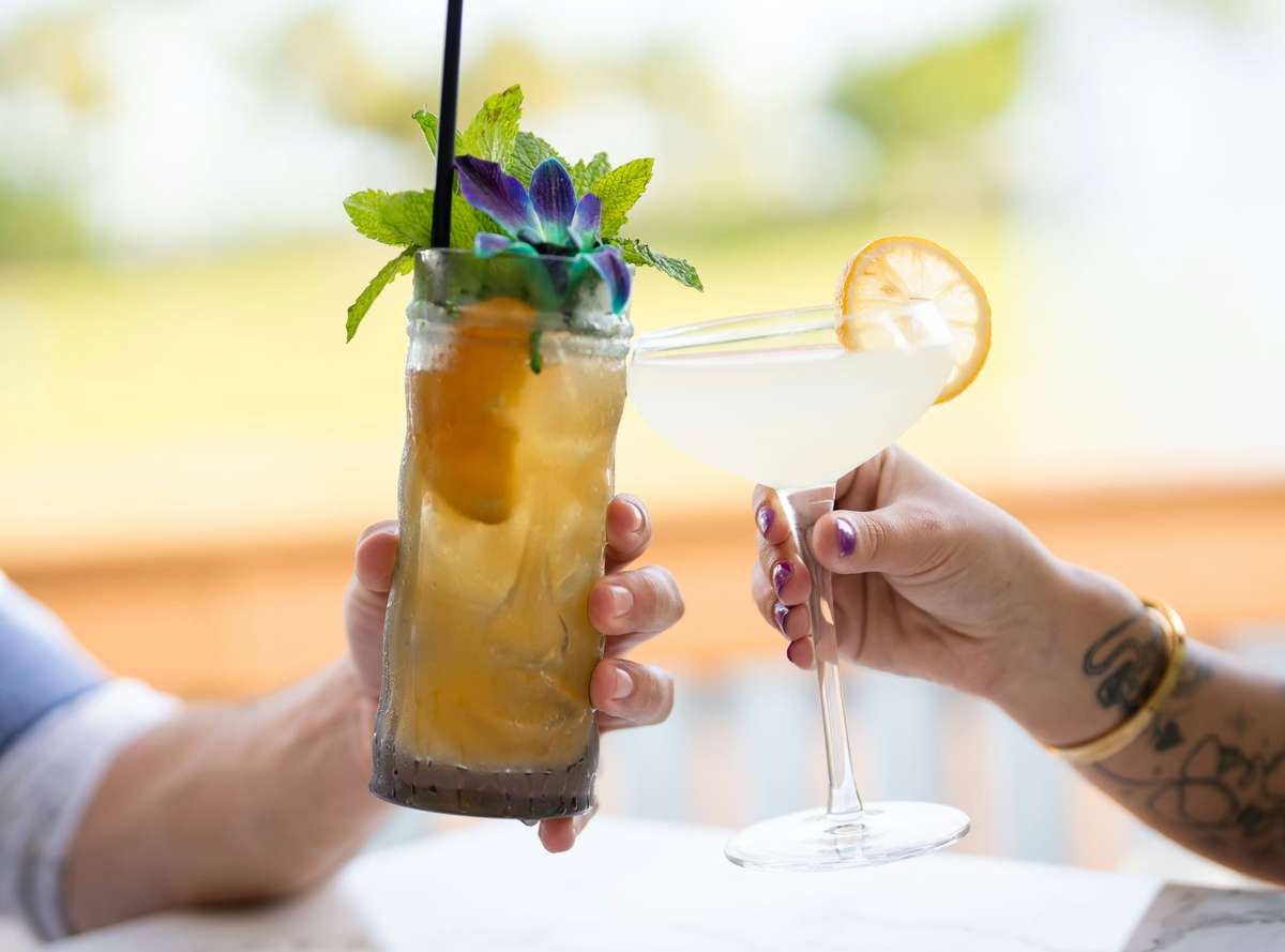 Two hands cheering cocktail glasses