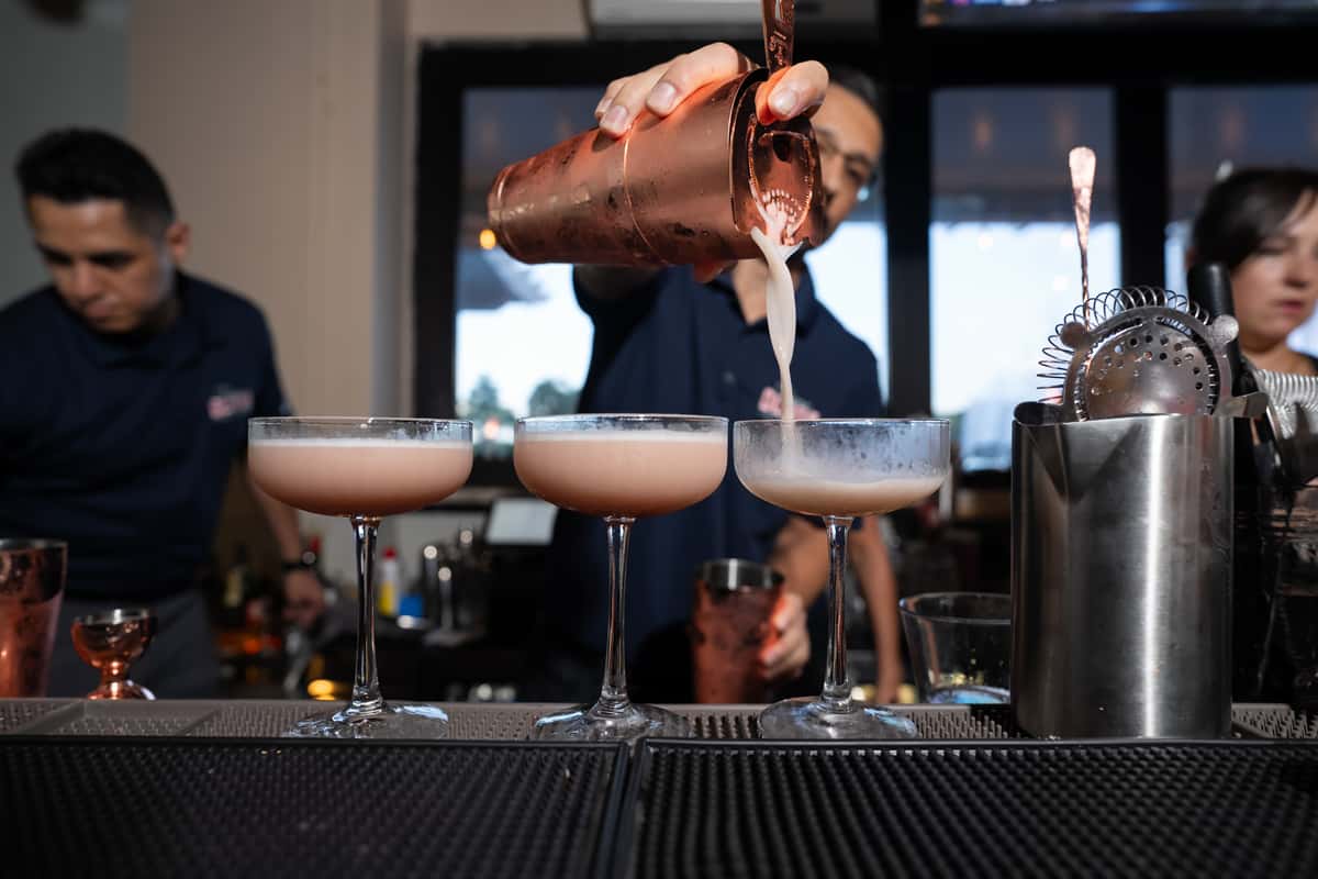 Bartender pouring three mixed drinks