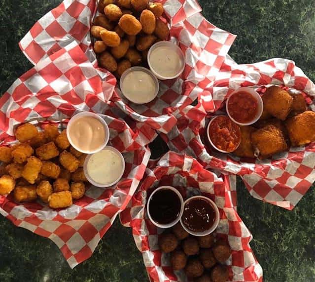 four baskets of assorted fried appetizers with dipping sauces