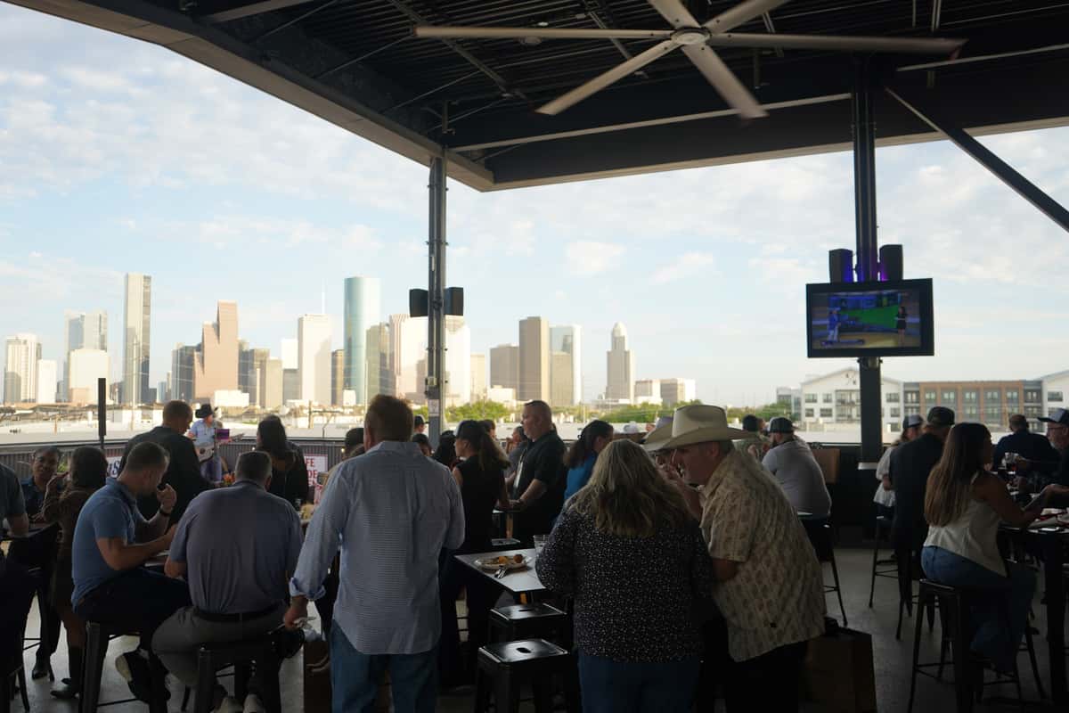 Guests gathered on the outdoor patio overlooking the city skyline during a restaurant event.
