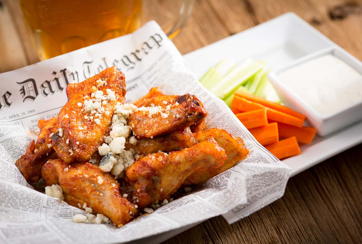 Fried chicken wings seasoned and served with a side of vegetables
