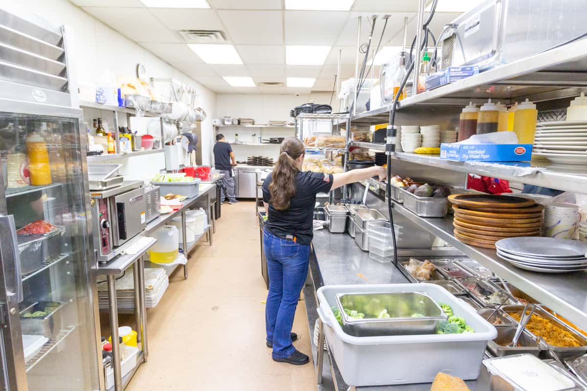 restaurant kitchen staff working at prep station with fresh ingredients in a busy commercial kitchen