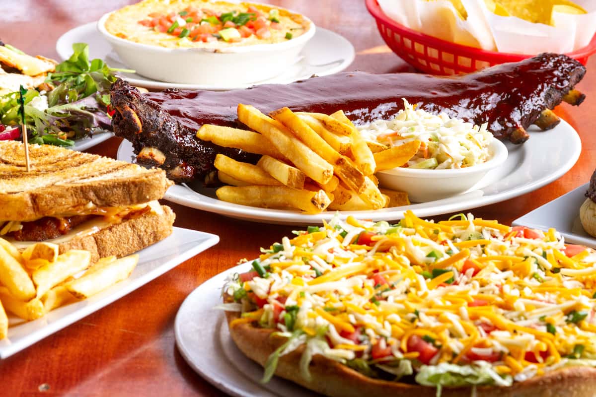 loaded nachos topped with melted cheese and fresh toppings served alongside burgers and fries on a casual dining table