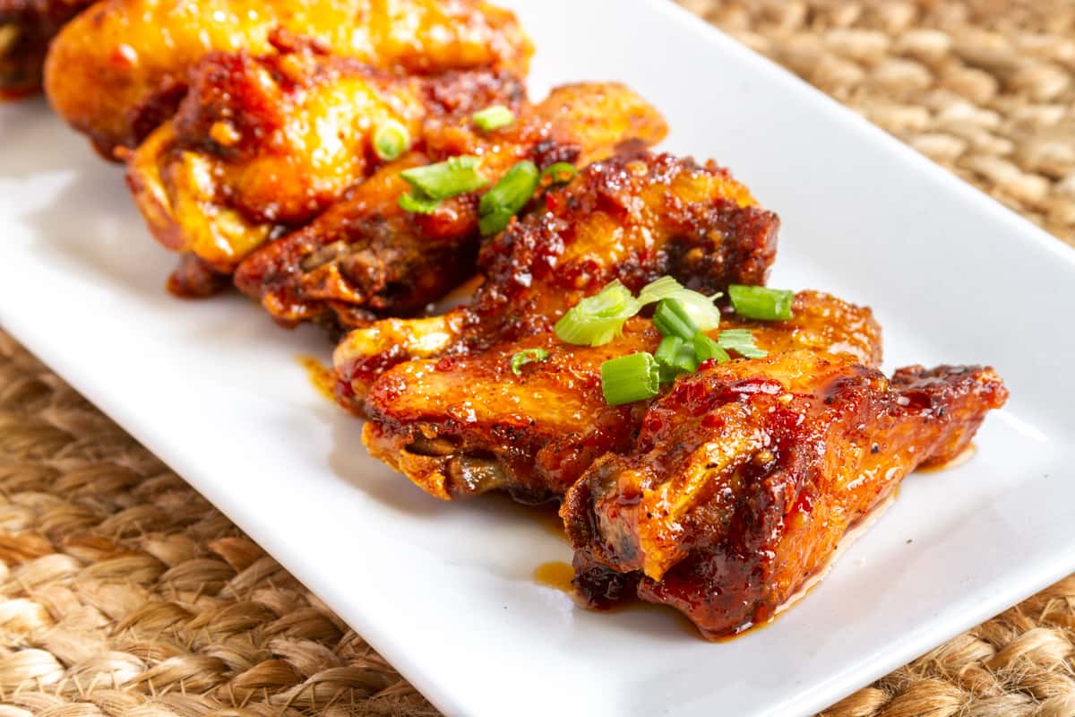 sweet Asian chili wings glazed with sauce and garnished with herbs on a white plate