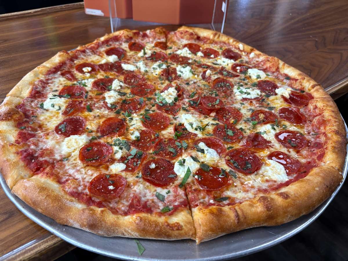 A large Gasparilla pepperoni and ricotta pizza with herbs on a silver pan.